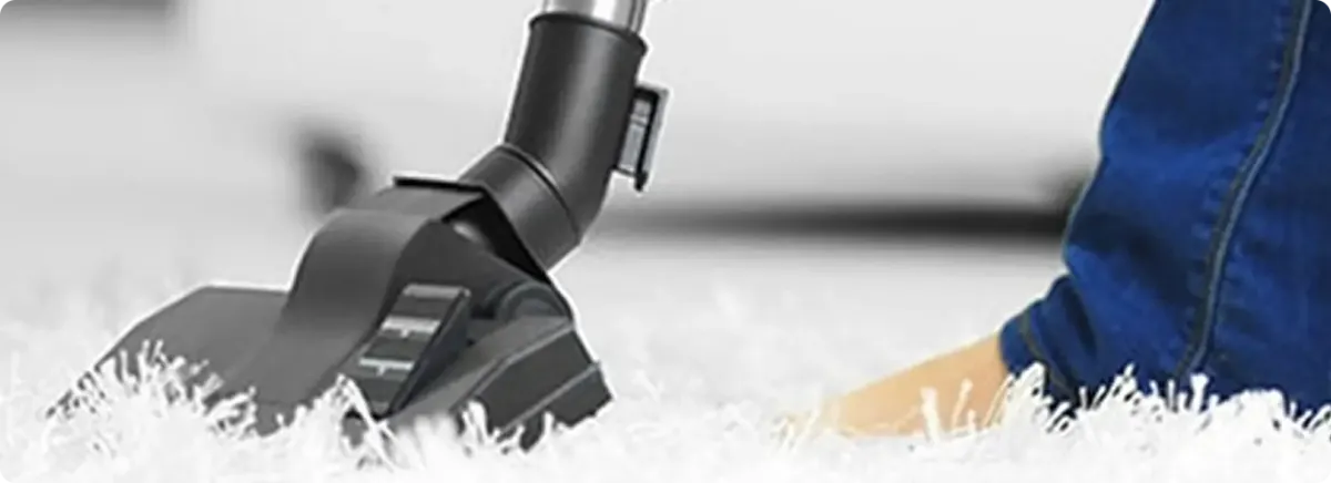 Close-up of a professional vacuuming a white carpet in Tewksbury.
